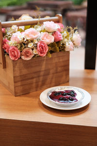 Hand on blueberry cheese cake with artificial flower bouquet on the wooden table
