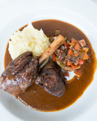 Close-up shot of roasted lamp shank with mashed potatoes on table