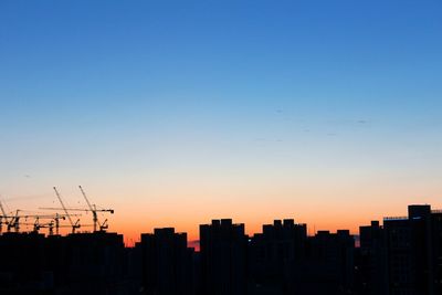 Silhouette buildings against clear sky during sunset