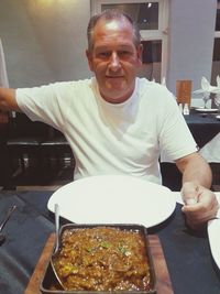 Portrait of smiling man holding ice cream on table