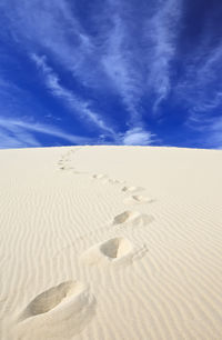 Sand dunes in desert against blue sky