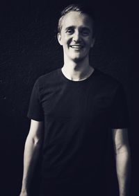 Portrait of a smiling young man against black background