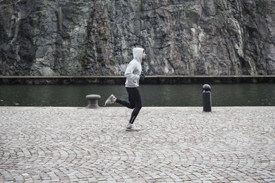 Man jogging on street against rock