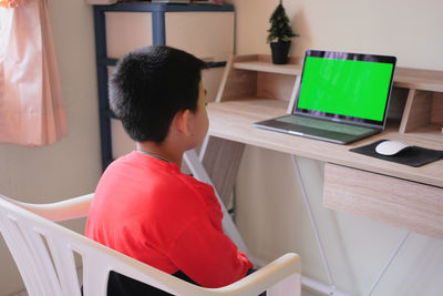 Rear view of man sitting on table at home