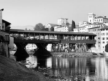 Bridge over river by buildings against clear sky