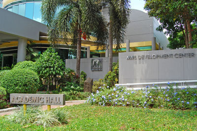 Information sign by trees and plants in front of building