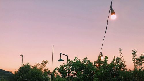 Low angle view of street lights against sky at sunset