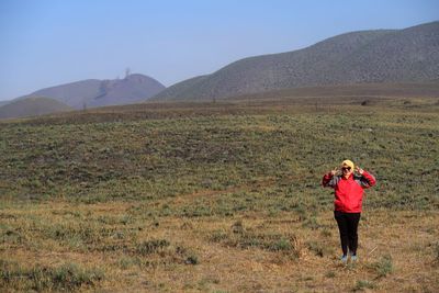 Rear view of man standing on field against sky