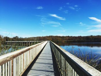 Footbridge over trees against blue sky