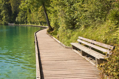 Wooden bench on footpath by lake