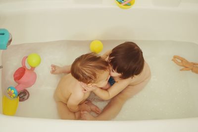 High angle view of siblings playing in bathtub