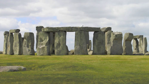 Old ruins on grassy field against cloudy sky