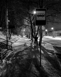 Road sign on snow covered street at night