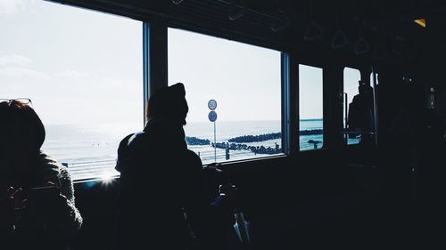 Silhouette woman photographing through window