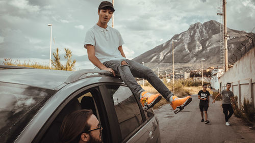 Young man and cars on mountain against sky