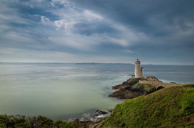 Lighthouse by sea against sky