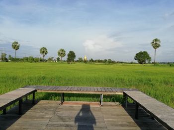 Park bench on field against sky