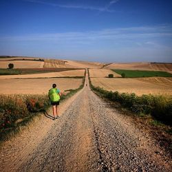 Rear view of woman walking on dirt road