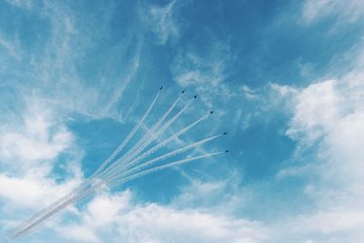 Low angle view of airshow in blue cloudy sky