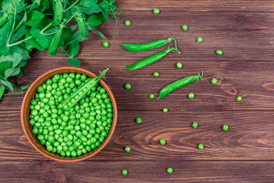 Fresh green peas in a bowl against the background of leaf shoots, sprigs of young green peas. 