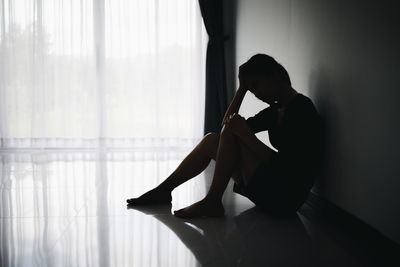 Low section of woman sitting on bed at home