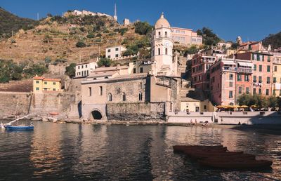 Boats in river by buildings in city against sky