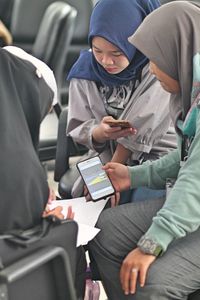 Female friends wearing hijab using smart phones