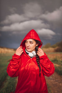 Woman standing on field against cloudy sky