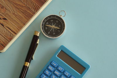 High angle view of navigational compass against blue background