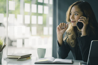 Businesswoman talking over smart phone while sitting in office