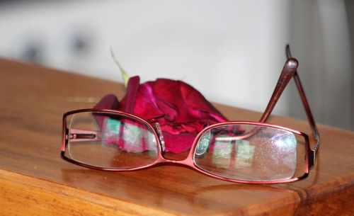 Close-up of eyeglasses and rose on table