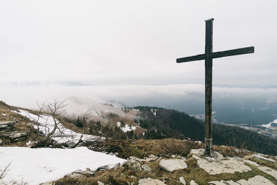 Cross on snowcapped mountain against sky