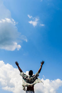 Low angle view of person with arms raised against sky