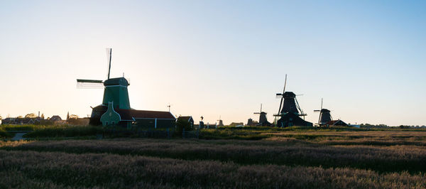 Traditional windmill on field against sky during sunset