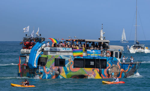 People on boats in sea against clear sky