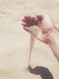 Cropped image of man pouring sand at beach