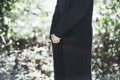 Midsection of woman standing by trees