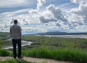 Rear view of man standing on land against sky