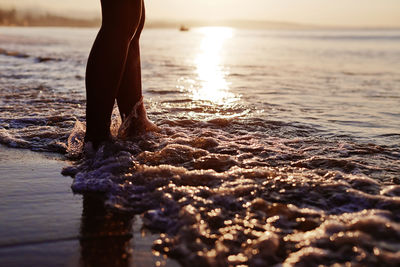 Low section of woman standing at beach