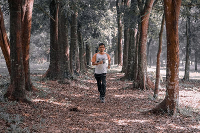 Full length of man standing amidst trees in forest