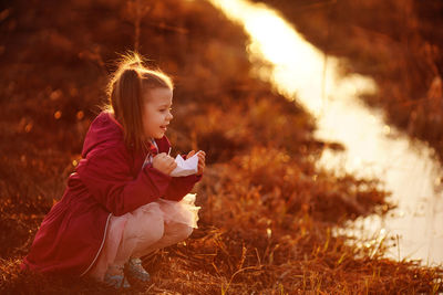 Girl in the spring on the creek launches paper boats