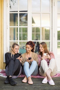 Female friends using mobile phones at summer house