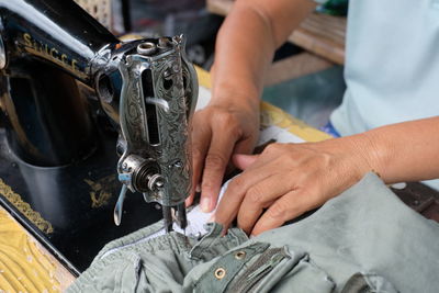 Midsection of person sewing textile on machine