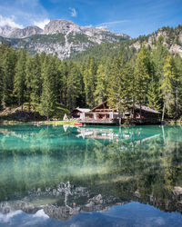 Scenic view of lake by trees and houses against mountains