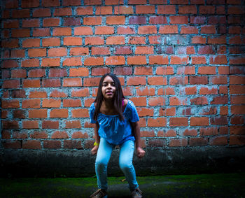 Young woman standing against brick wall