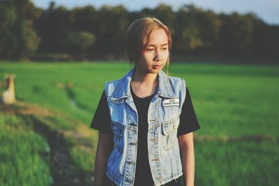 Portrait of young woman standing on field