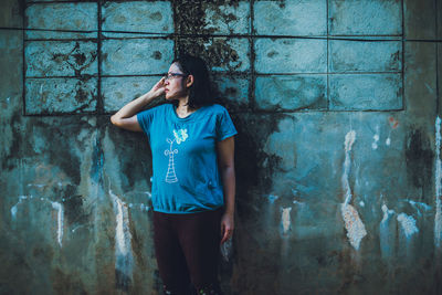 Young woman looking away against wall