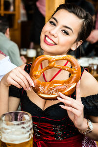 Portrait of beautiful woman holding pretzel at oktoberfest