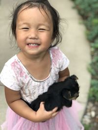 Portrait of smiling cute girl carrying puppy