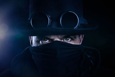 Close-up of man wearing mask against black background